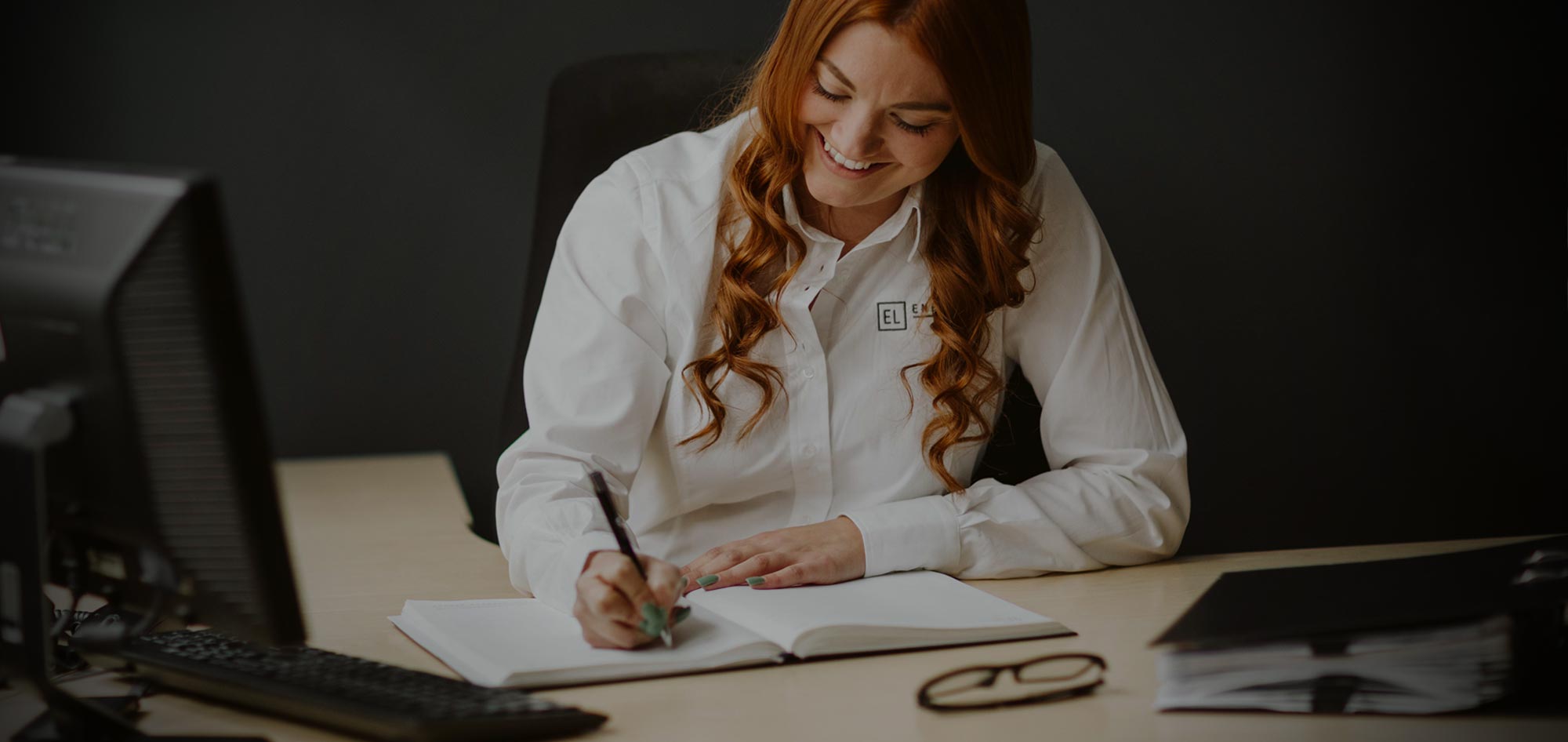 Caitlin Smith, Senior Client Executive at Enfields Luxe writing in a notebook at her work desk